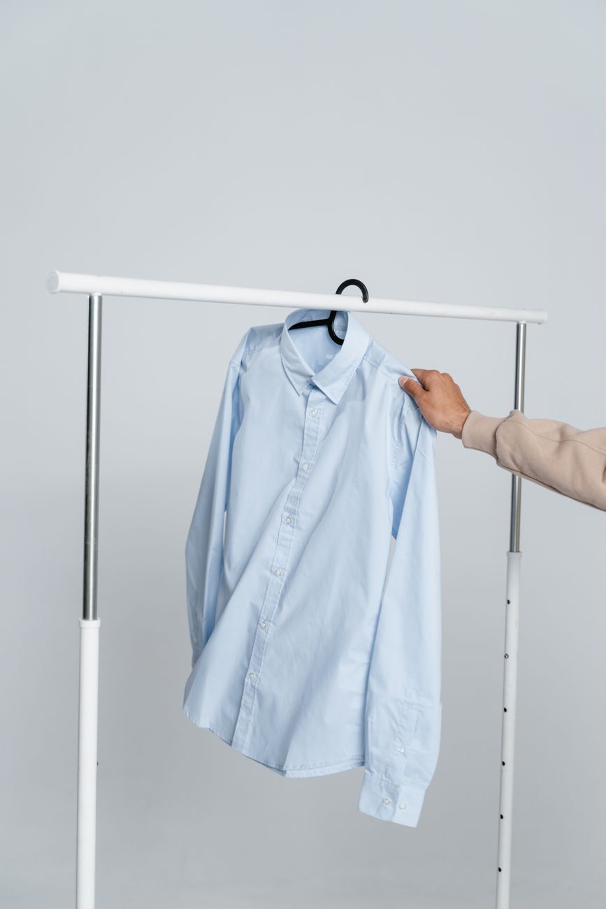 Persona eligiendo una camisa azul elegante en una percha