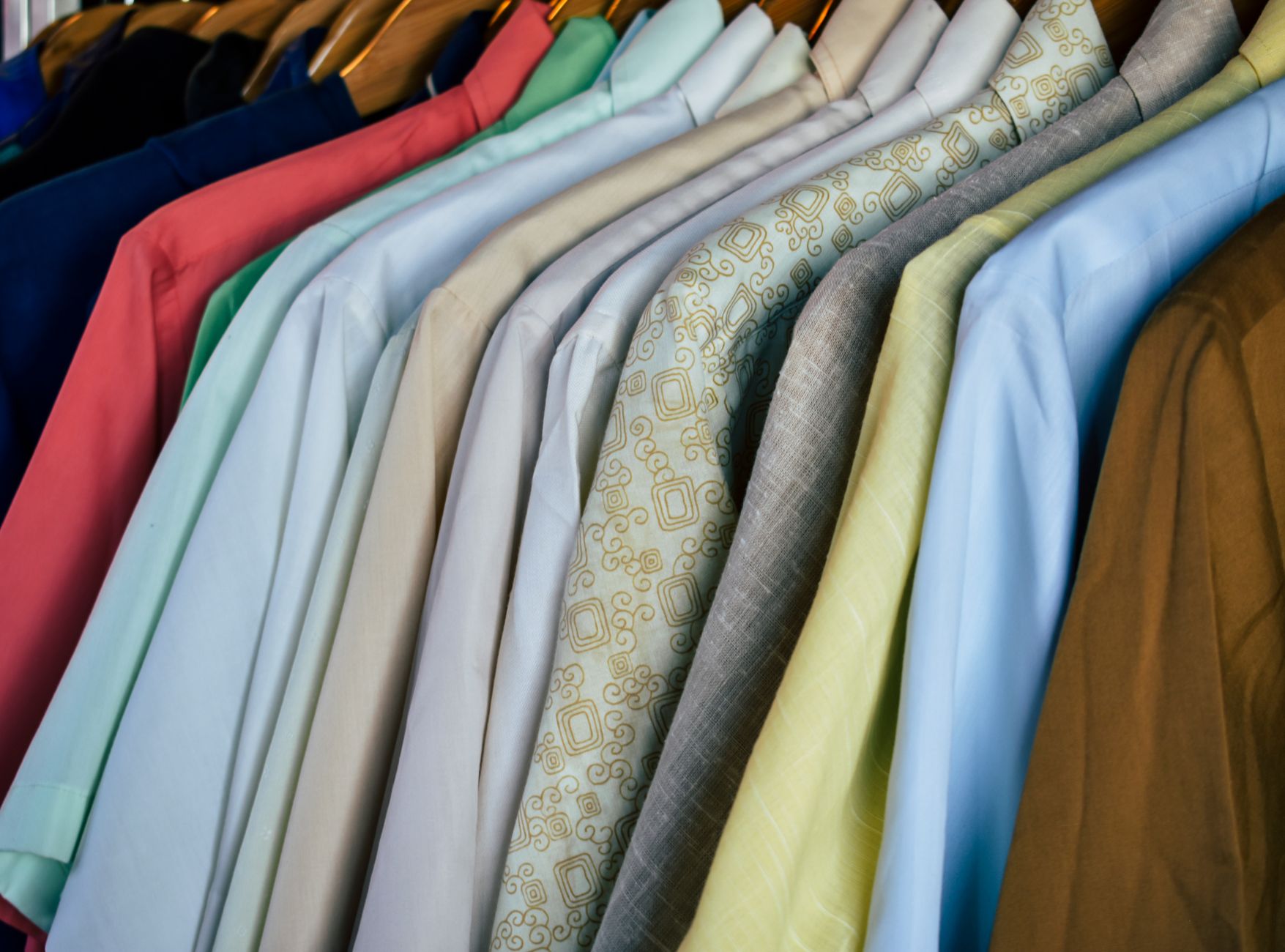 Camisas de colores colgadas en perchas de madera